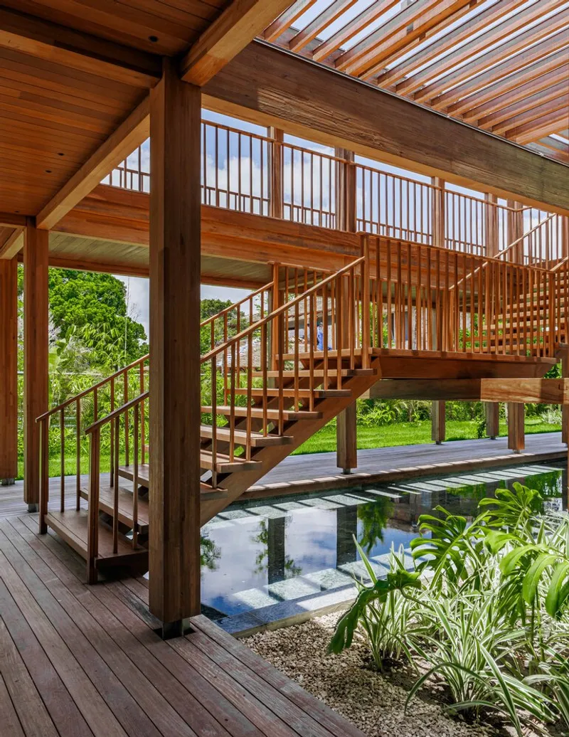 Timber staircase with slatted balustrade crossing over a reflecting pool beneath a louvered skylight