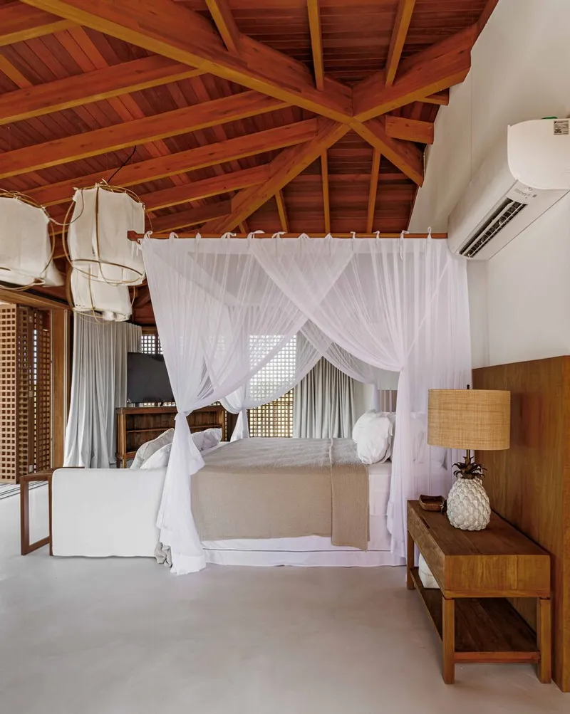 Bedroom interior with exposed timber ceiling beams and a white canopy bed under fabric pendant lights