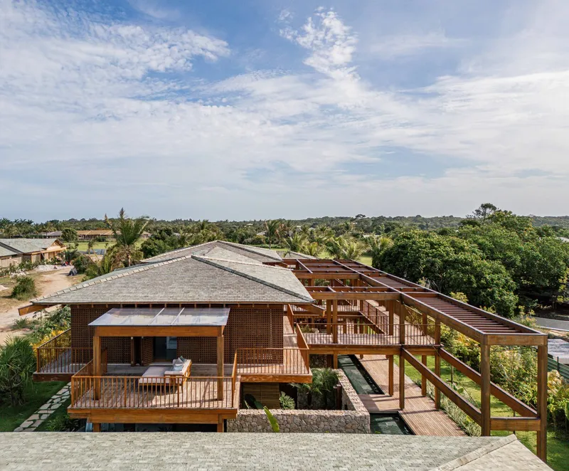 Elevated view of the timber frame structure with perforated brick screen and terraced decks overlooking green landscape