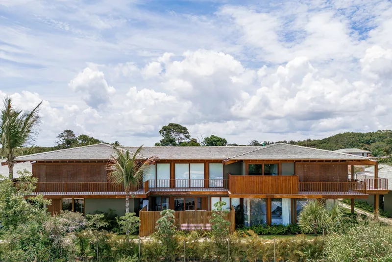 Long elevation showing continuous hipped roof over timber-framed upper level and planted landscape below