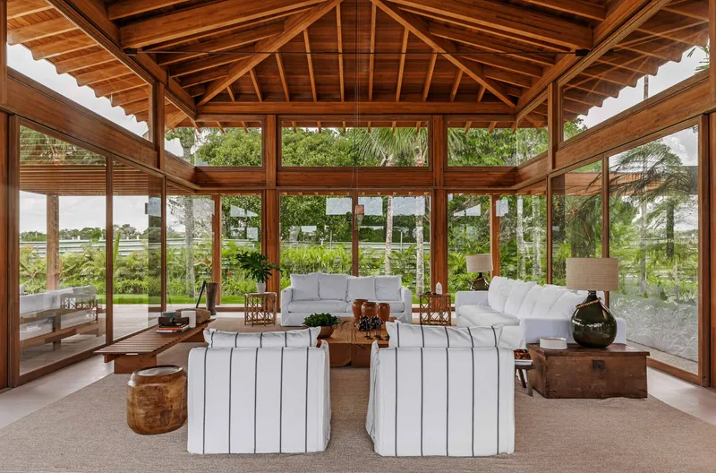 Glazed pavilion with exposed timber roof trusses and rafters opening onto a lawn and planted garden