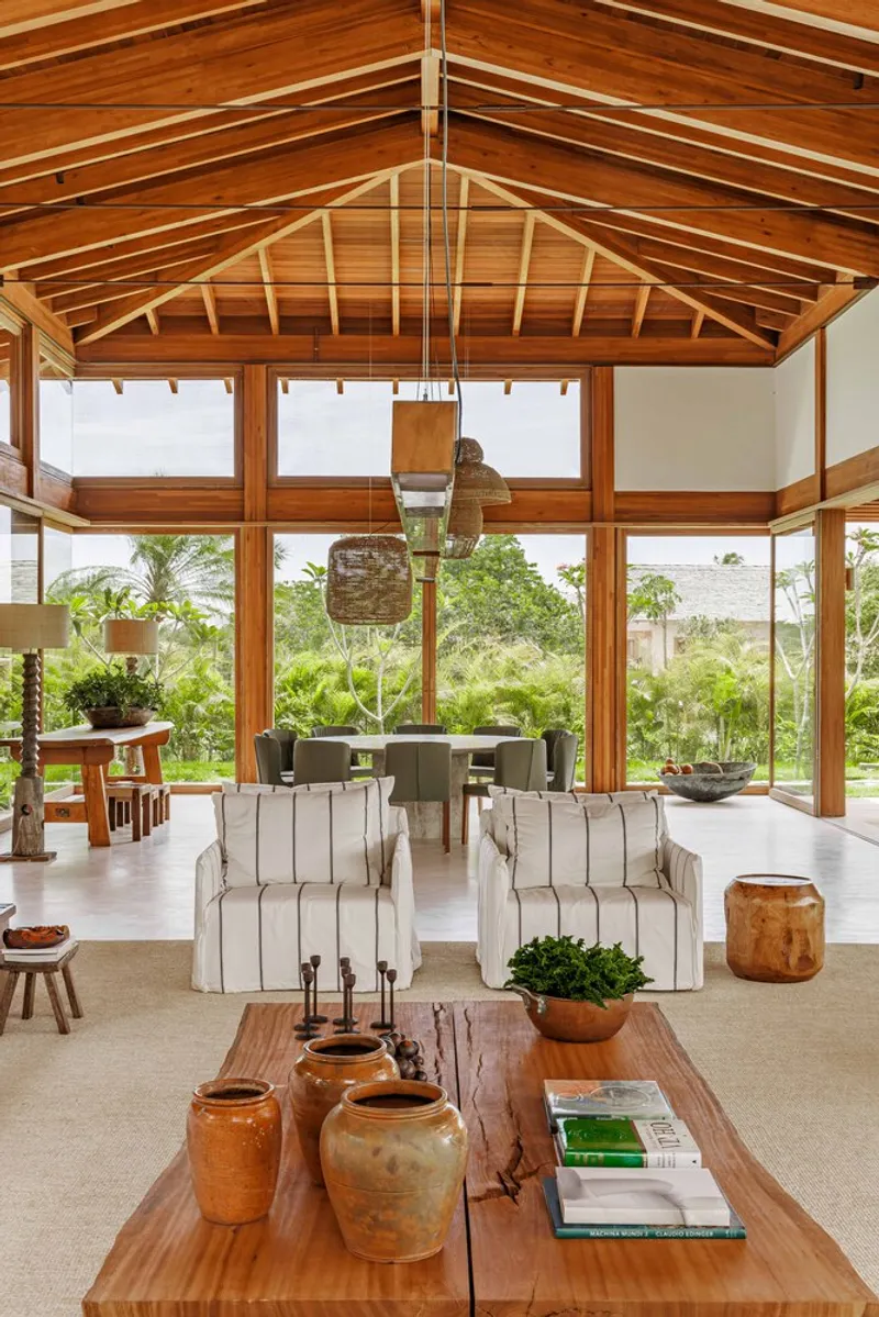 Open pavilion interior with gabled timber ceiling and continuous clerestory windows framing tropical vegetation