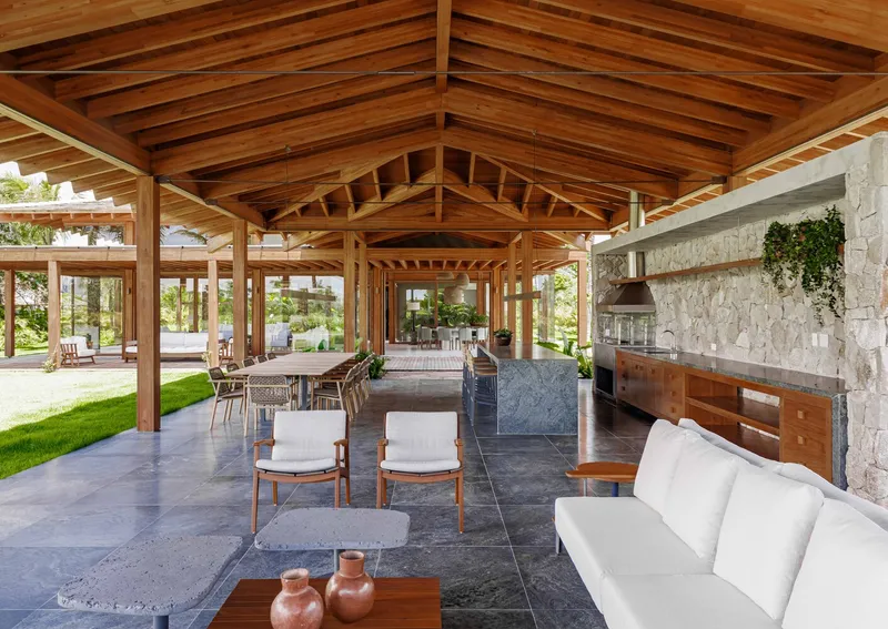 Long view through timber pavilion showing stone fireplace wall and axial sequence of gabled volumes