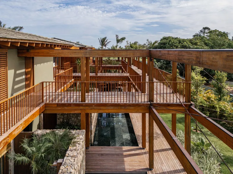 Elevated timber walkway bridging over a reflecting pool framed by stone walls and planted beds