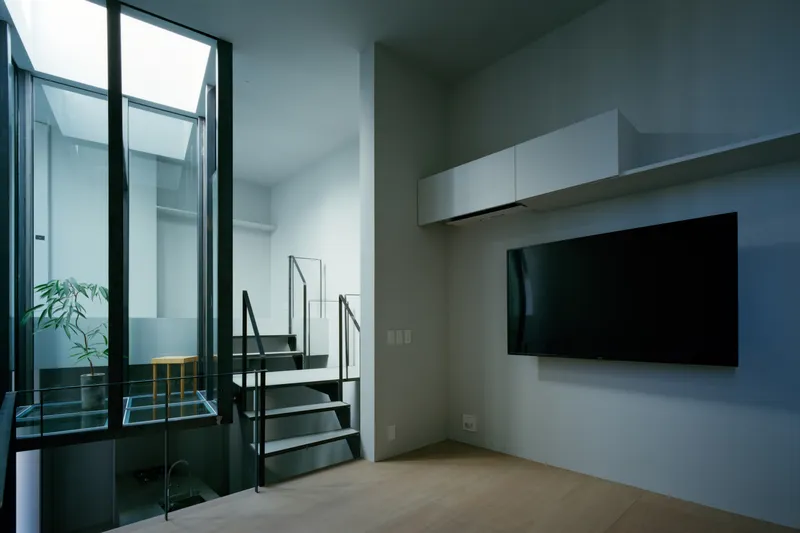 Living area with glass courtyard opening and steel stair in background under skylights