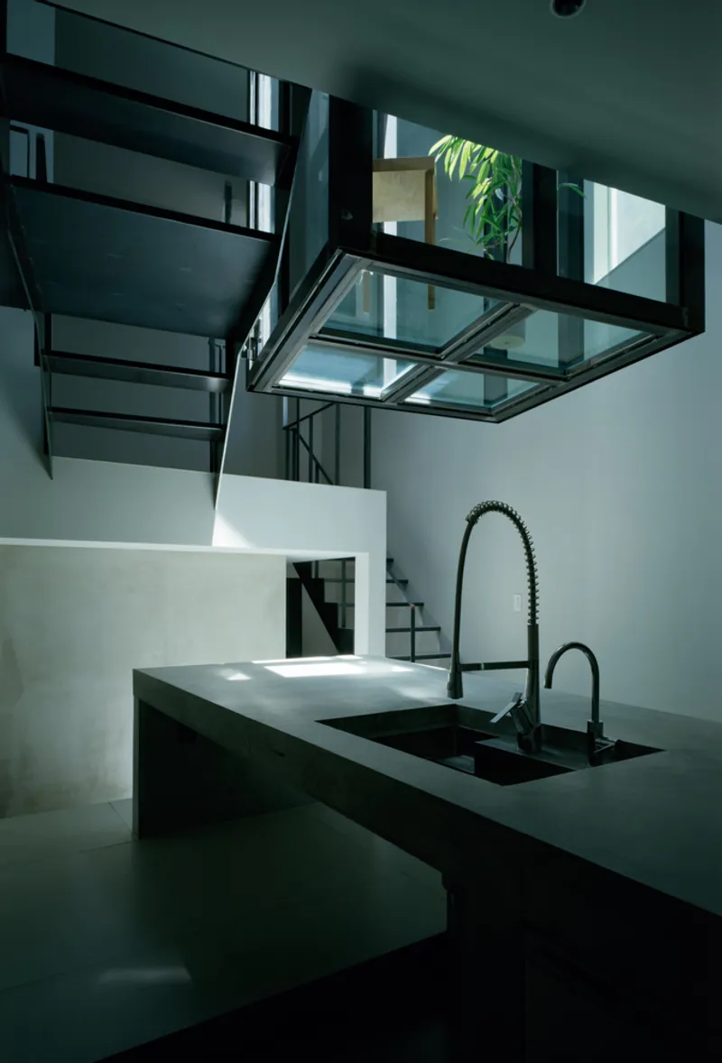 Kitchen counter looking toward steel stair and glass bridge structure in diffused daylight