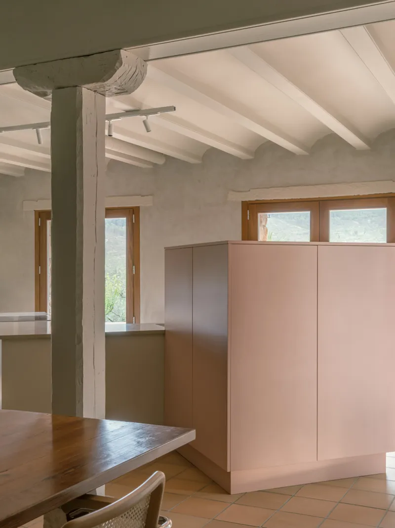 Interior kitchen with pink cabinetry, timber column, exposed ceiling beams, and terracotta floor tiles