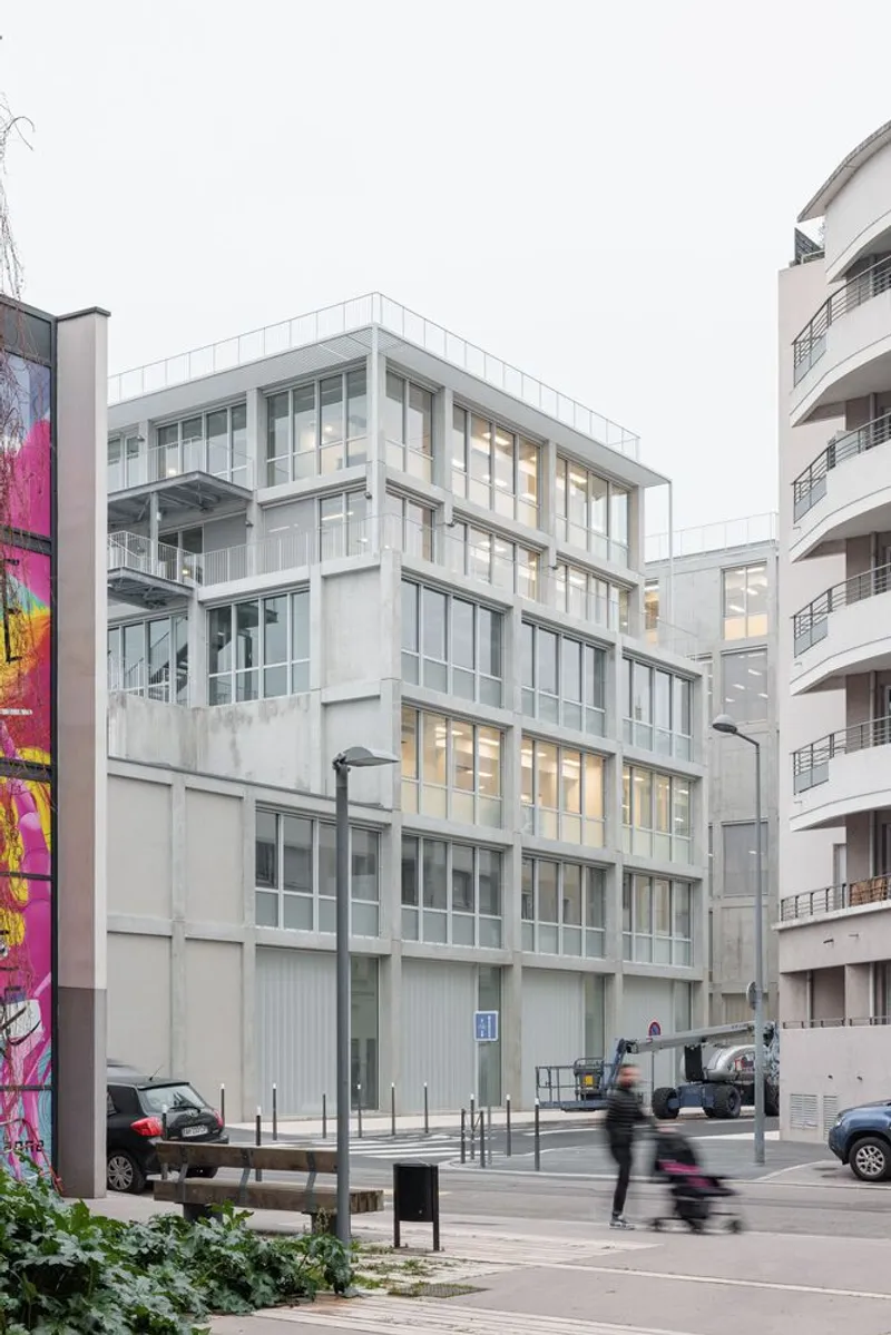 Corner facade with stacked glazing and concrete panels as pedestrians cross the street below