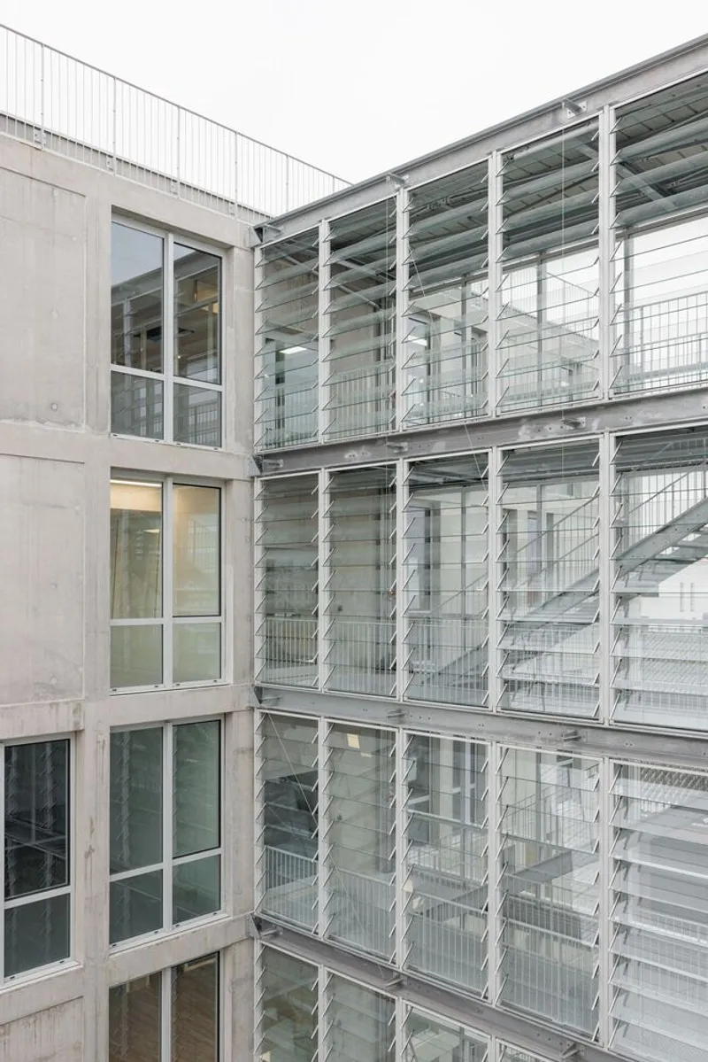 Interior courtyard with perforated metal stairs and operable glass louvre wall opposite concrete volume