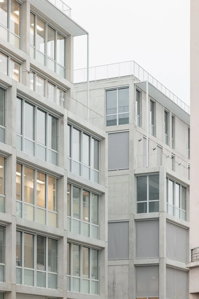 Street view of the concrete and glass facade with large windows under an overcast sky