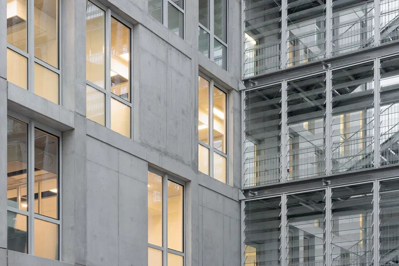 Close-up of concrete panels and glazed openings adjacent to an exposed steel structure