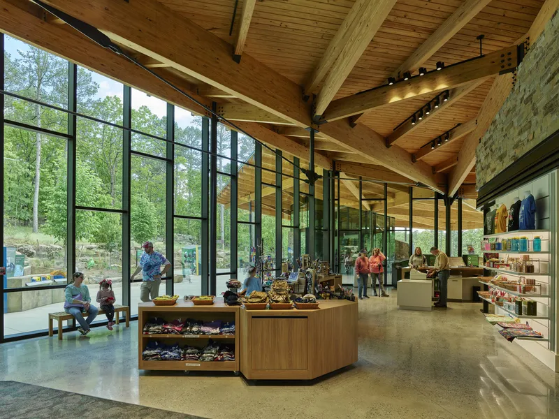 Gift shop interior with laminated timber ceiling beams, black steel columns, and floor-to-ceiling glazing