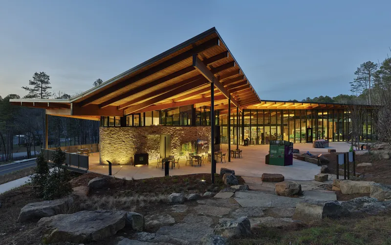 Covered terrace with uplighted stone wall and exposed timber roof structure at dusk