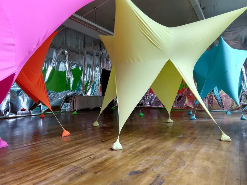 Close view of yellow star-shaped fabric canopy with taut guy lines and colored anchor weights