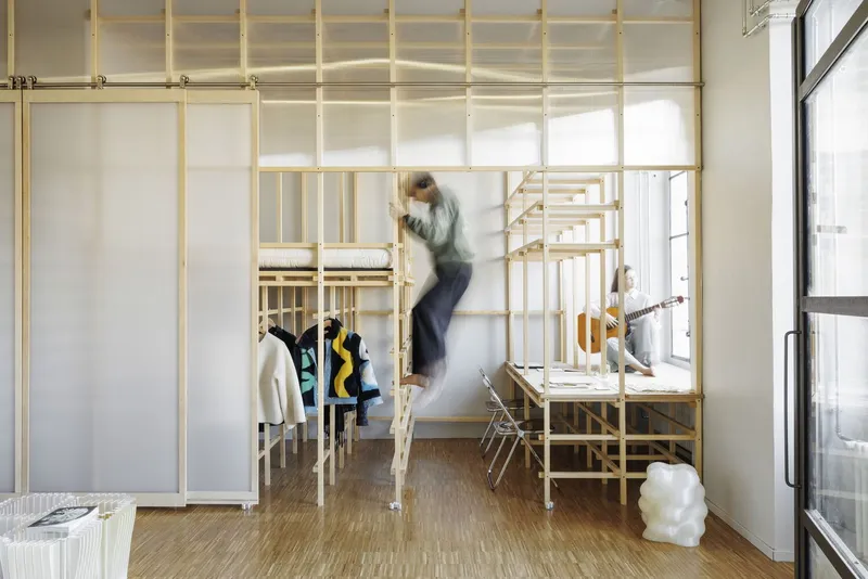 View through a translucent panel partition showing a blurred figure in motion within the timber framework