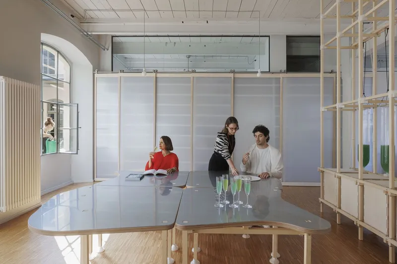 Conference table with mirrored surface where three people gather beside a timber and translucent panel partition
