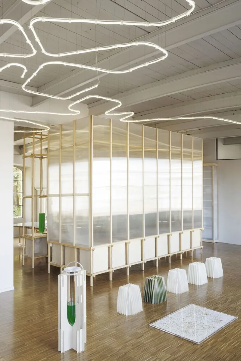 Long view of the translucent timber pavilion with vertical glass bioreactor tubes and wavy ceiling lights