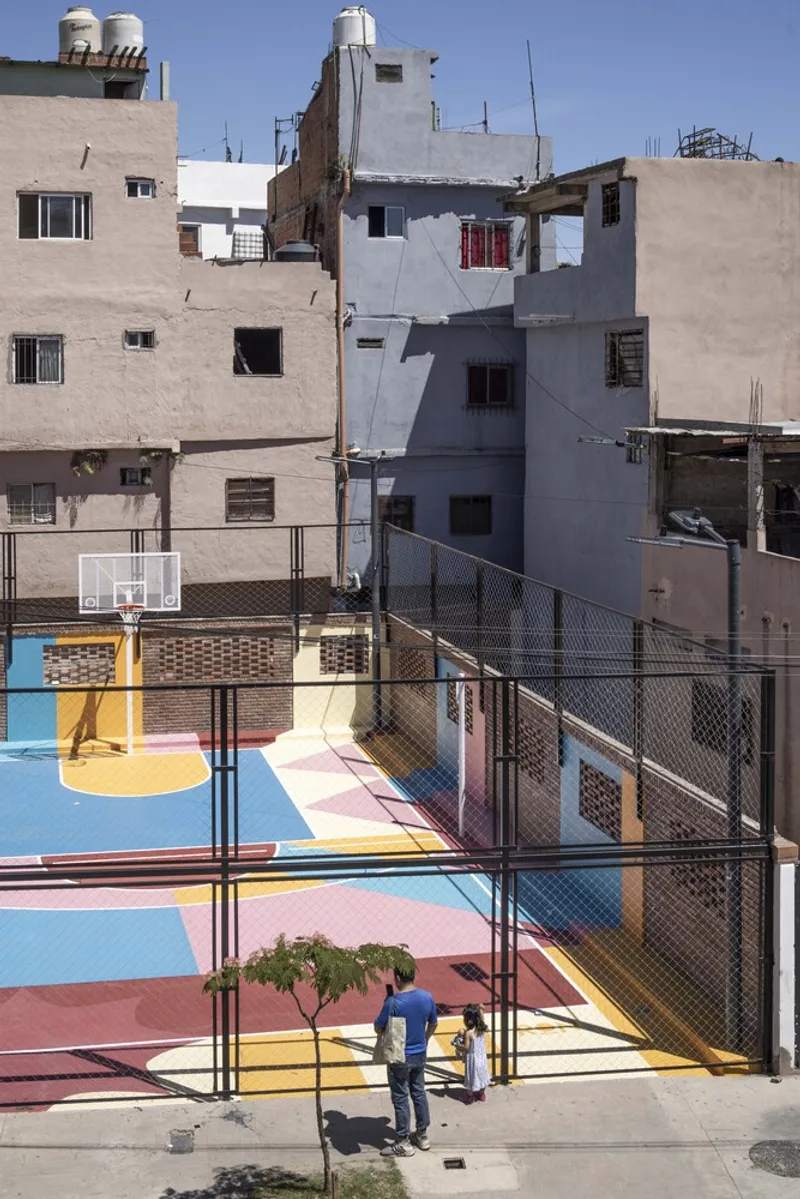 Ground-level view of the painted basketball court with two children and adjacent residential structures