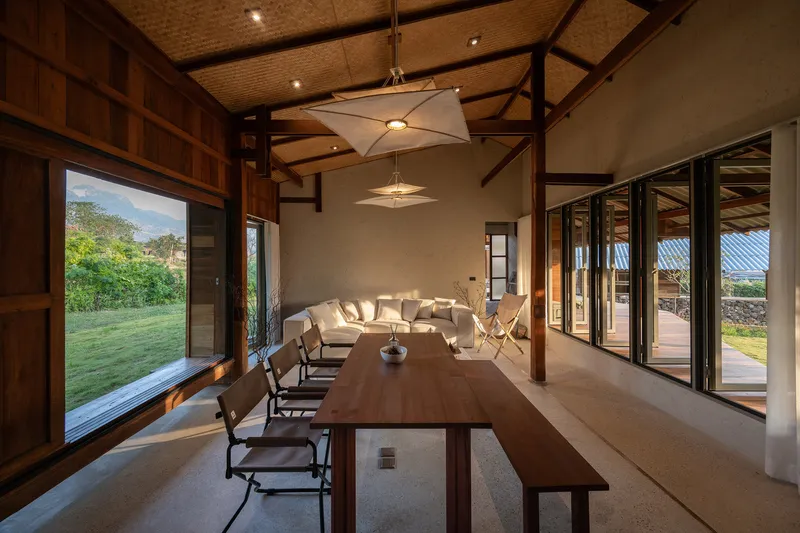 Dining and living room with exposed timber frame and folding glass doors opening to lawn