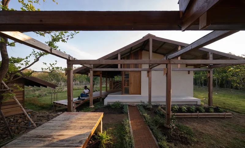 Courtyard view of white plaster walls and timber door beneath a pergola at dusk