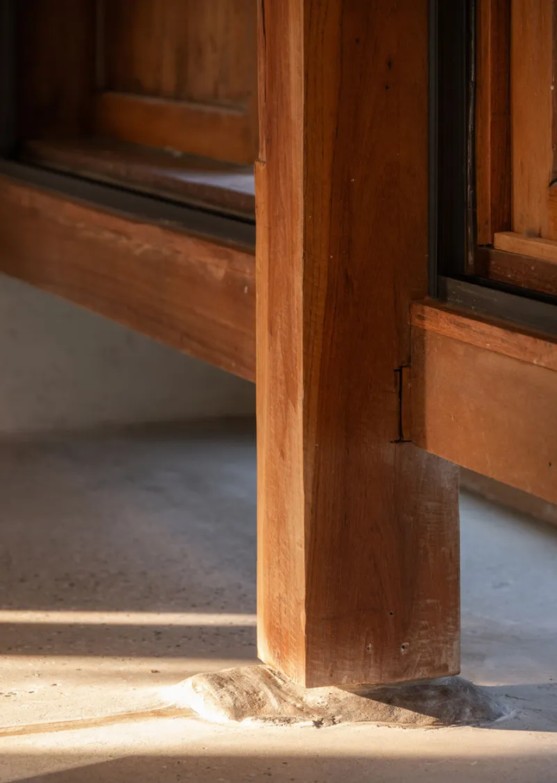 Detail of a timber post meeting a stone threshold in warm afternoon light