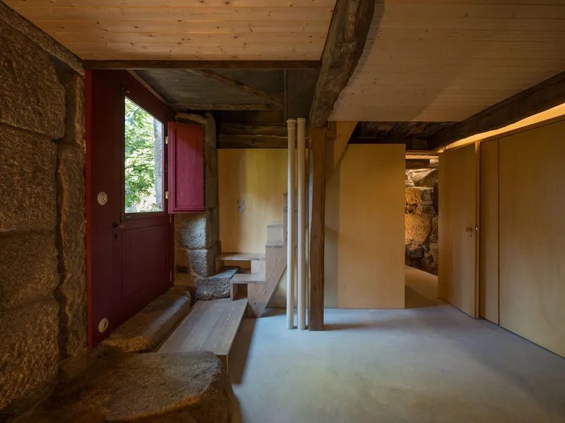Entry vestibule showing stone steps descending from a burgundy door with exposed timber ceiling beams