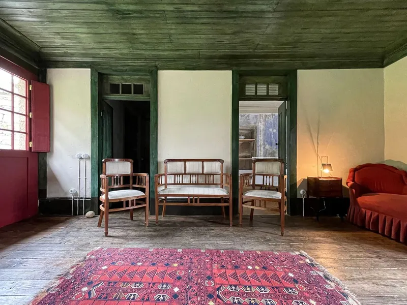 Living room with cane furniture on wide timber floorboards beneath a dark green painted ceiling