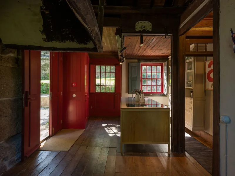 Entry hall with red painted doors, timber structure, and open kitchen island in morning light
