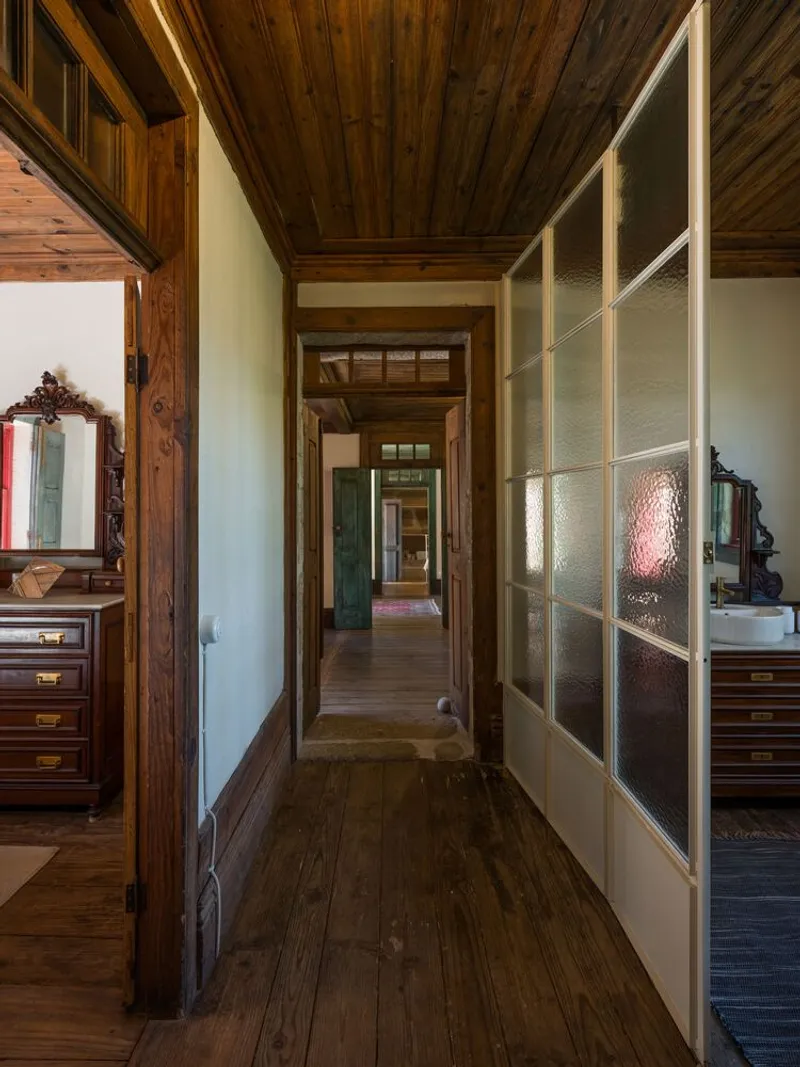 Hallway with timber plank ceiling and textured glass partition wall flanked by dark wood flooring