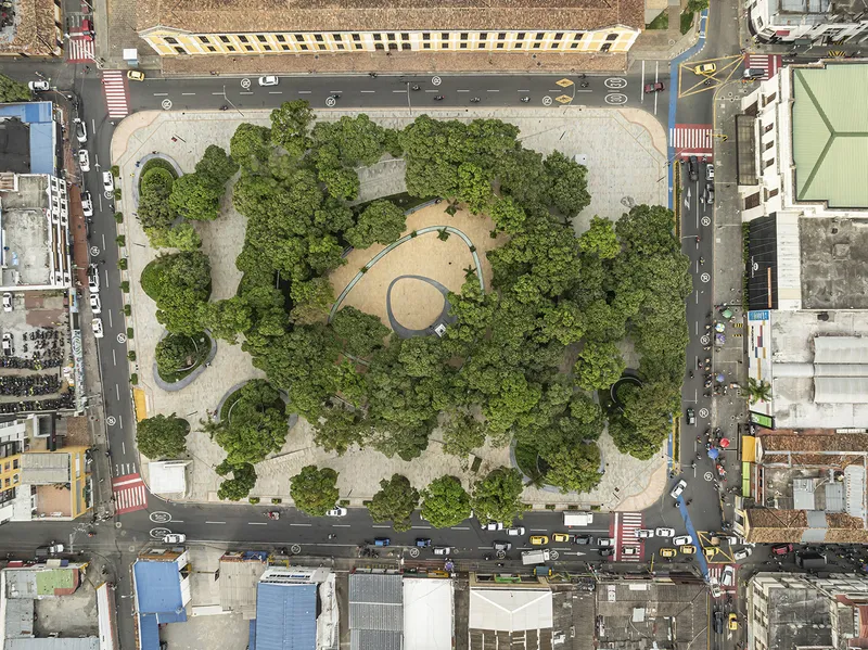 Aerial view of the tree-filled plaza with circular paving patterns surrounded by urban streets and buildings