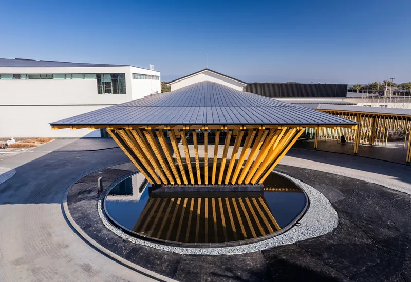 Top view of the freestanding timber canopy with ribbed metal roof and circular reflecting pool below