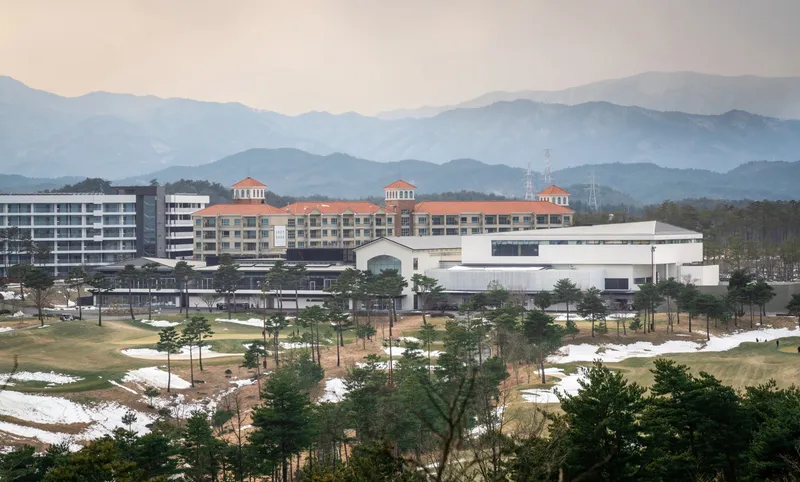 Wide view of the white box volume beside residential blocks with mountains in hazy distance