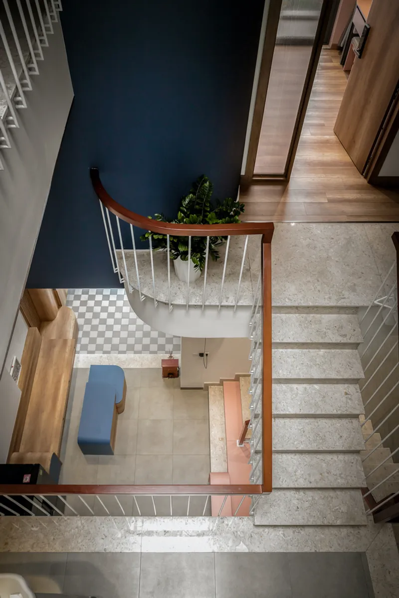 Top-down view of curved staircase with timber handrail and potted plant on terrazzo landing