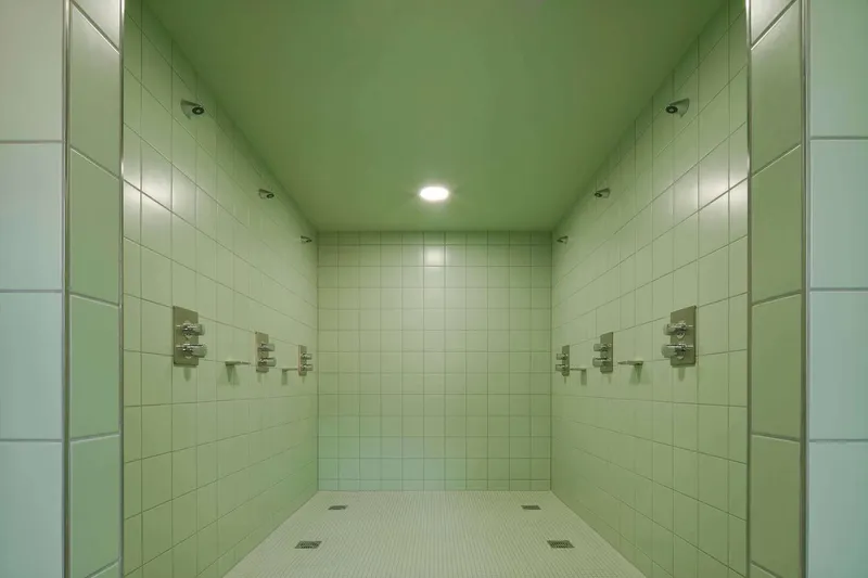 Tiled shower room with green ceiling and symmetrical wall-mounted fixtures under central recessed light