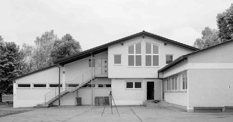 Courtyard elevation showing white rendered facade with gabled volume, external stair to upper floor and glazed entrance