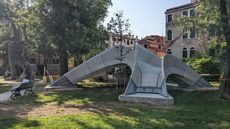 Side view of the folded metal canopy structure on concrete base in afternoon light
