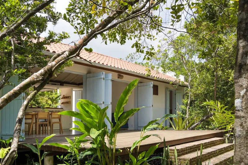 Raised timber deck and terracotta roof pavilion surrounded by banana plants and overhanging tree branches