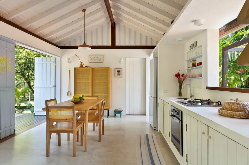 Kitchen and dining area with exposed timber rafters, white painted ceiling boards and concrete floor