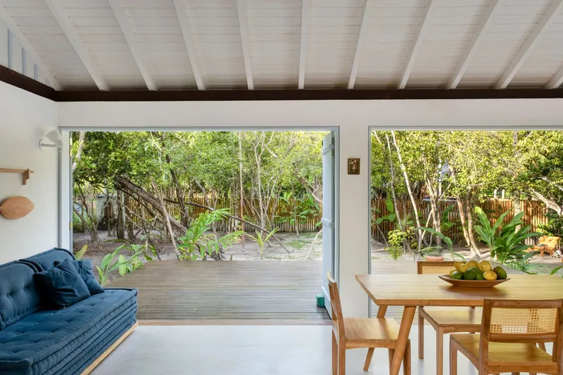 Living area opening through sliding doors to a timber deck and garden beyond