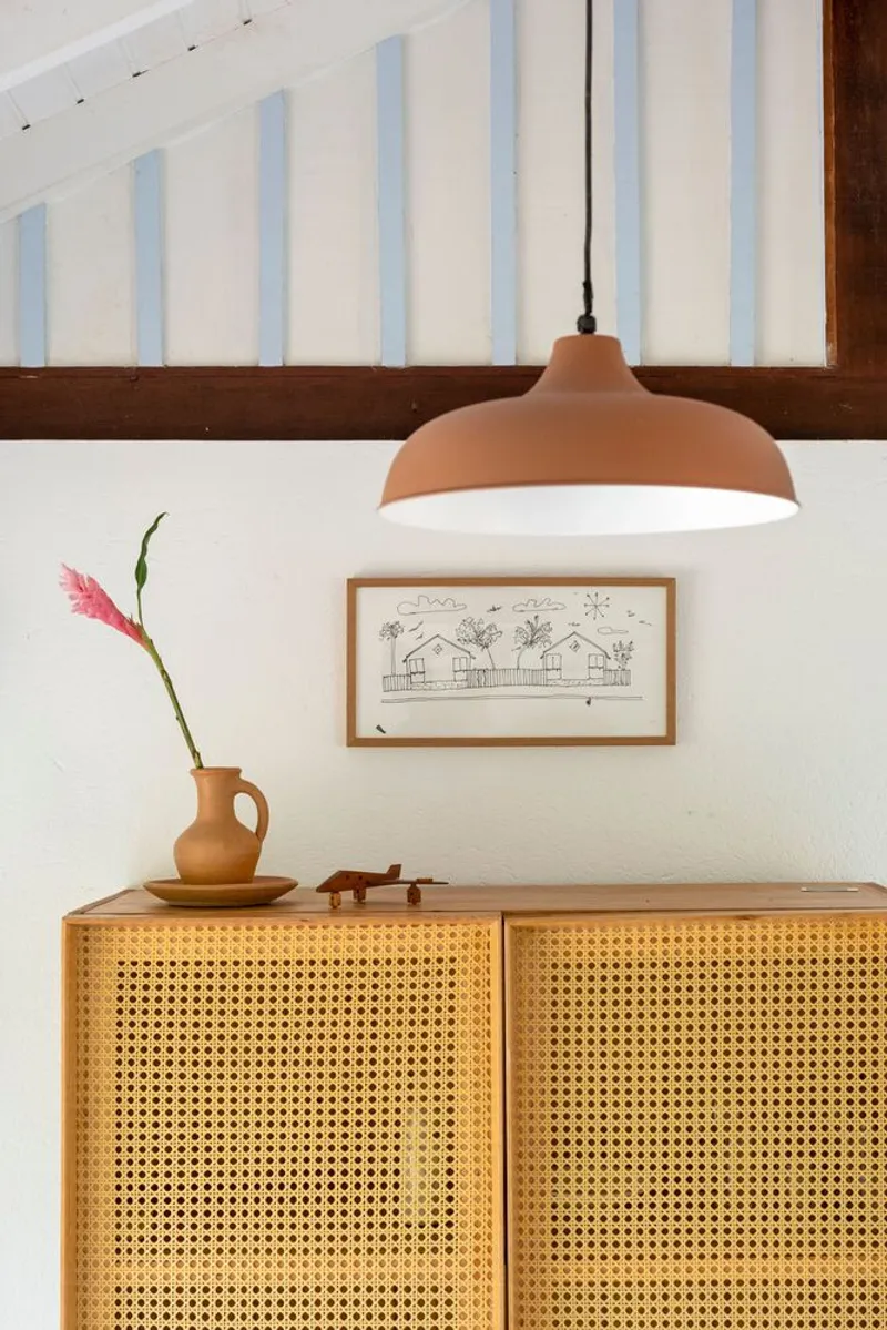 Cane-fronted cabinet beneath a terracotta pendant light and exposed timber structure above