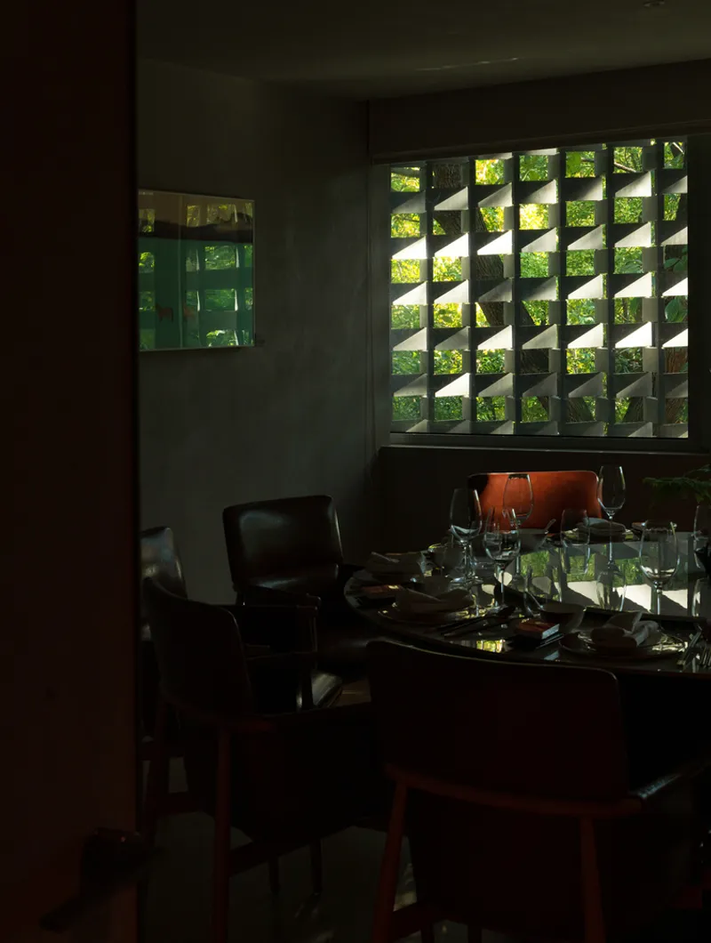 Corner dining area with patterned masonry screen filtering sunlight from the garden outside