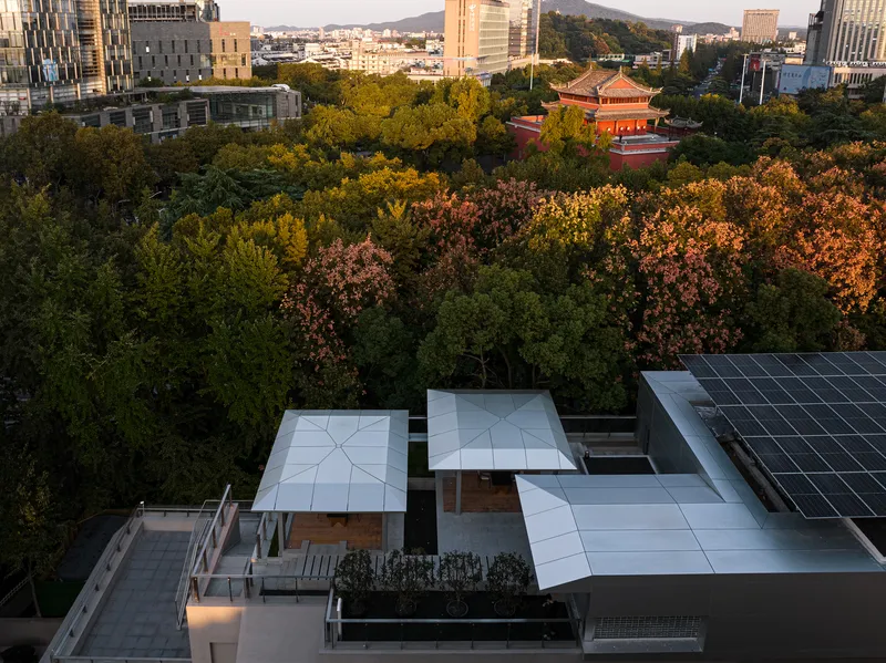 Aerial view of white paved terrace roof with solar panels overlooking tree canopy at golden hour