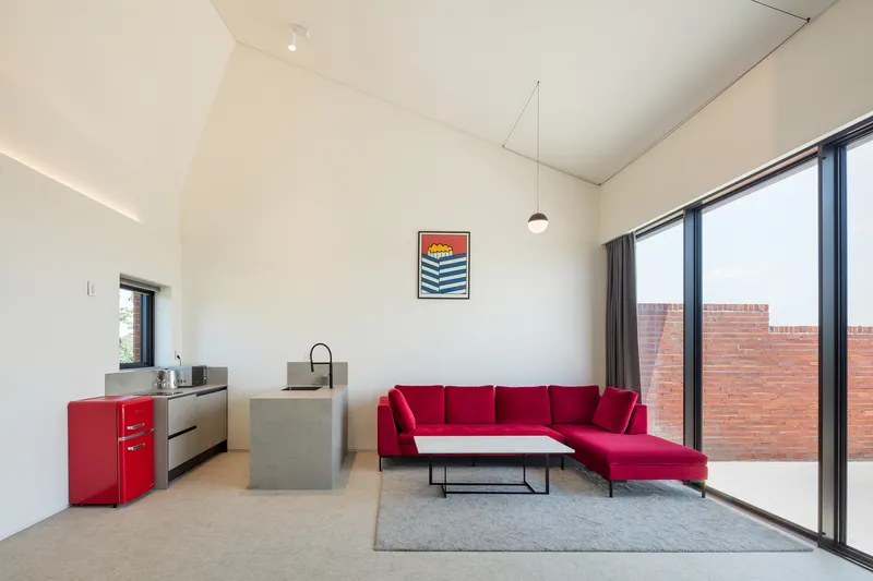 Living space with vaulted ceiling and concrete island overlooking a red brick courtyard through glazed doors