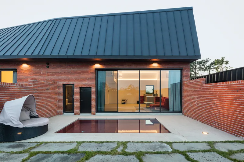 Private courtyard with reflecting pool surrounded by red brick walls at twilight