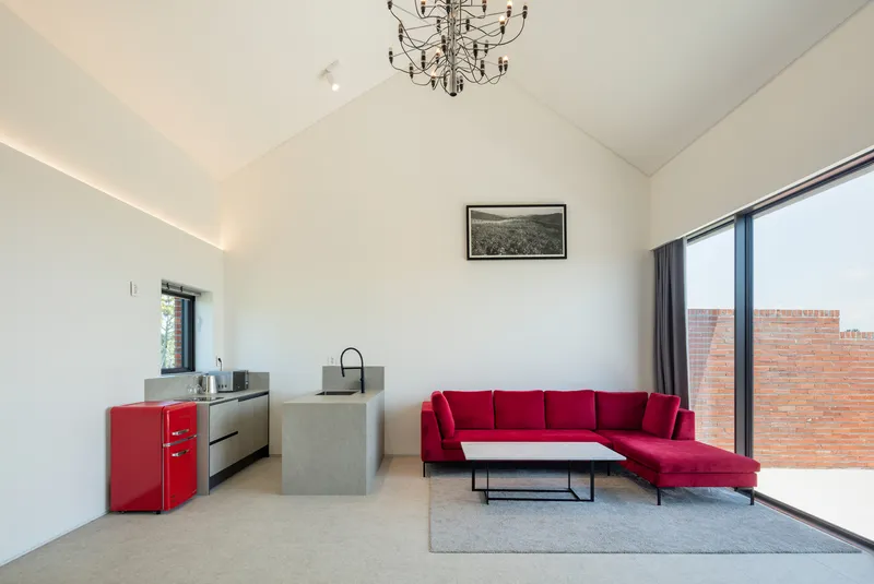 Open living space with vaulted ceiling and full-height glazing overlooking the brick courtyard