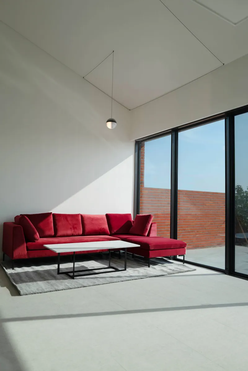 Interior corner with afternoon sunlight entering through the floor-to-ceiling glazed doors