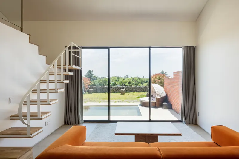 Living space with curved white staircase and sliding glass doors opening to a terrace with pool
