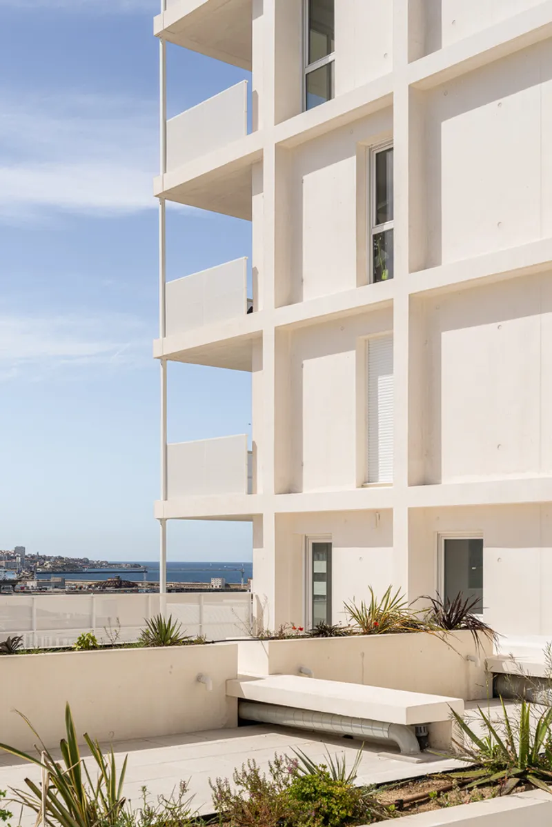Rooftop terrace with concrete bench and planted beds overlooking the ocean horizon