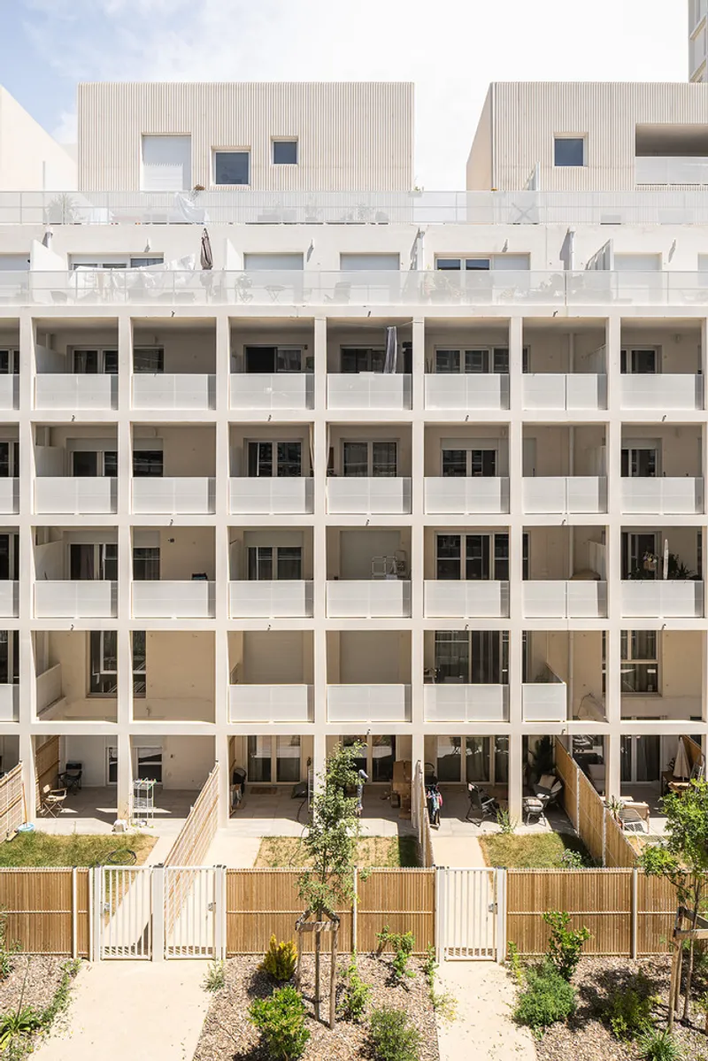 Courtyard facade showing the stacked balconies with wooden slatted screens and young trees below