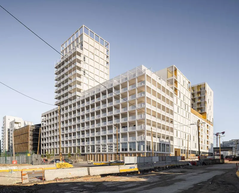 Corner view of the stepped residential complex with tower and podium at an active construction site